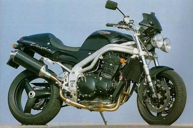 <div class='descrGalleryTitle'>Speed Triple T509</div><div class='descrGalleryText'><p>La primissima Speed Triple, la T301 a faro singolo, era arrivata nel 1994; ma è stata la T509 a dar vita al <b>mito Speed Triple</b>. Vide la luce nel 1997 e portò con sé un tratto estetico (che all'epoca chiamarono <b>&quot;sguardo allucinato&quot;</b>) che oggi, quasi trent’anni più tardi, ancora ritroviamo nelle naked a marchio Triumph. La prima Speed Triple era fortemente caratterizzata da un <b>doppio faro tondo che ha fatto storia</b> e che non è cambiato, se non di una virgola, fino al 2011, quando la seconda serie di 1050 introdusse i nuovi gruppi ottici a diamante. La T509, ideata <b>con l’importante contributo di Carlo Talamo, </b>più che un semplice importatore, nasceva come una Daytona spogliata e semplificata e riuscì in un compito davvero arduo: <b>attirare l’attenzione in un segmento dominato dalla Ducati Monster. </b>Tanto quanto l’italiana, l’inglesina aveva carattere da vendere, con forme morbide ma aggressive e con lo spettacolare <b>forcellone monobraccio</b> che lasciava a vista il bel cerchio a tre razze. Poi il motore&nbsp;<i>triple</i>, con una voce unica e inconfondibile e un carattere particolare che fondeva il buono dei due e dei quattro cilindri. A dare una grossa spinta a livello marketing ci fu il ruolo da <b>protagonista in Mission Impossible II</b>, in cui Tom Cruise gioca con una Speed Triple nera come se fosse una moto da cross.</p>
</div>